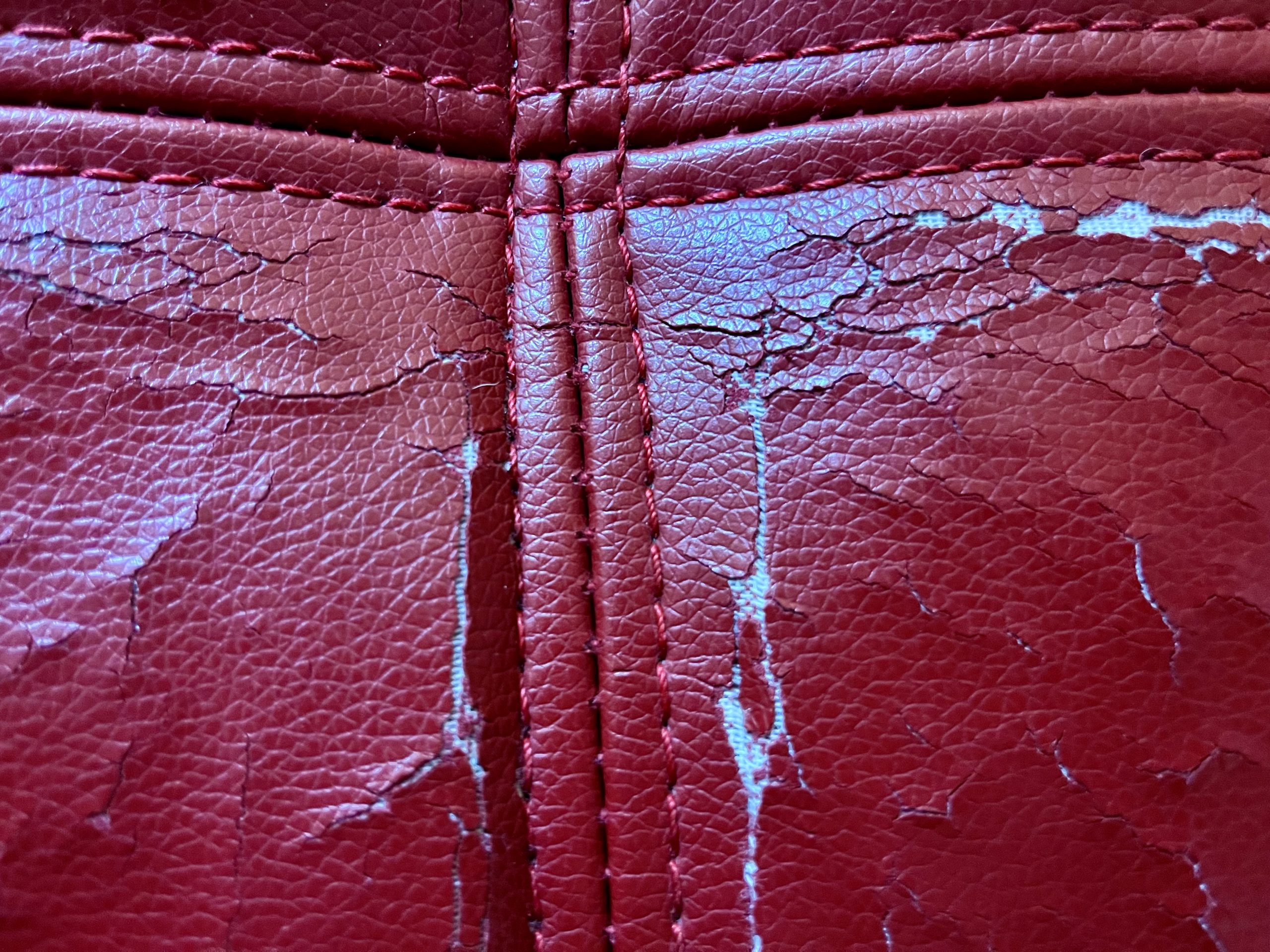 Close-up photo of the Coddle Toggle couch seams, showing cracked leather after about 3.5 years of normal use